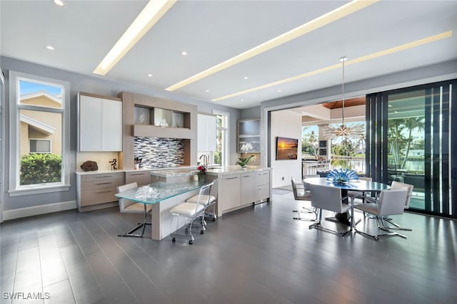 kitchen featuring white cabinets, decorative backsplash, hanging light fixtures, a large island, and light stone counters