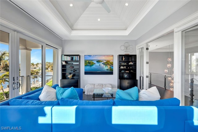 living room with a raised ceiling, ornamental molding, wooden ceiling, and french doors