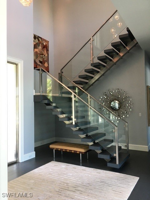 staircase with wood-type flooring and a high ceiling