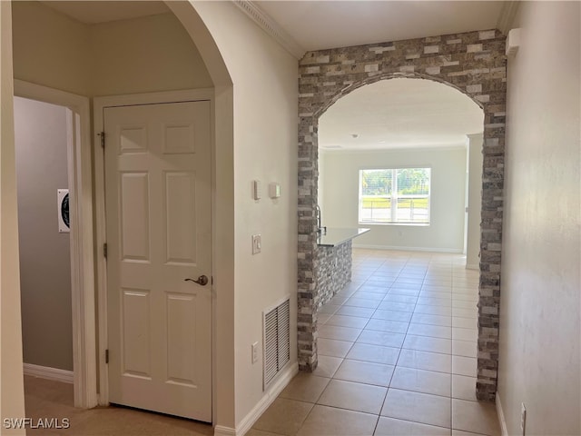 hallway featuring crown molding and light tile patterned flooring