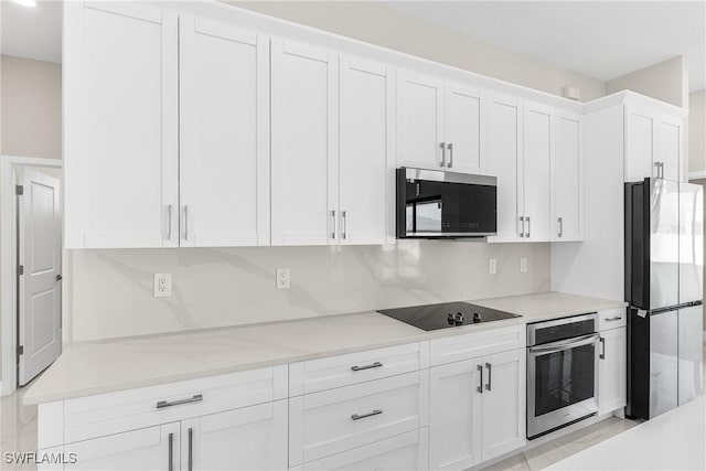 kitchen with decorative backsplash, stainless steel appliances, and white cabinets