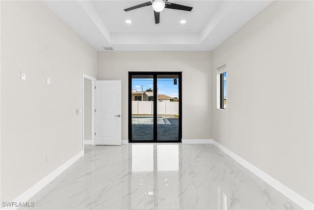 spare room featuring a tray ceiling and ceiling fan