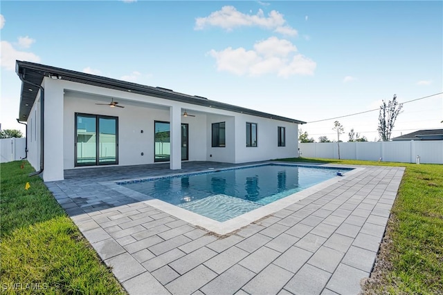 view of swimming pool with ceiling fan, a patio, and a lawn