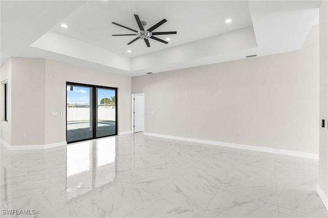 spare room featuring a raised ceiling and ceiling fan