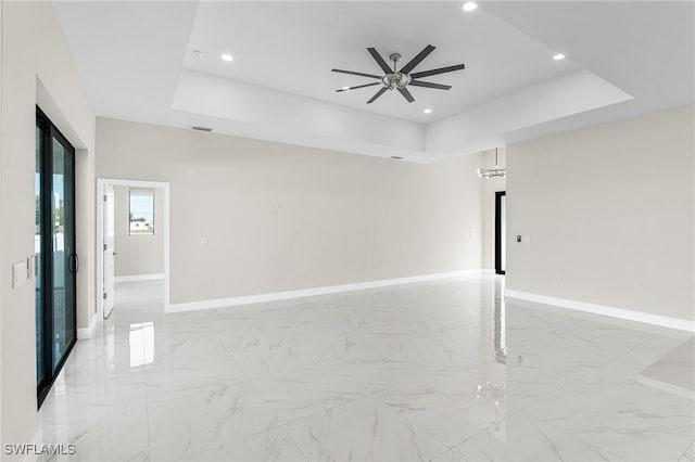 spare room with a raised ceiling and ceiling fan