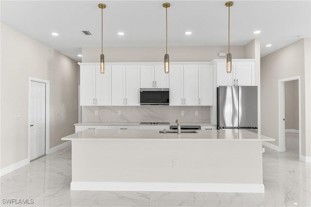 kitchen featuring white cabinetry, decorative light fixtures, a center island with sink, and appliances with stainless steel finishes