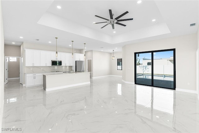 unfurnished living room with a raised ceiling, sink, and ceiling fan