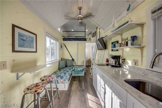 kitchen featuring light hardwood / wood-style floors, white cabinetry, wood ceiling, and sink