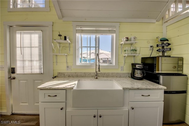 kitchen featuring light stone counters, plenty of natural light, white cabinets, and sink