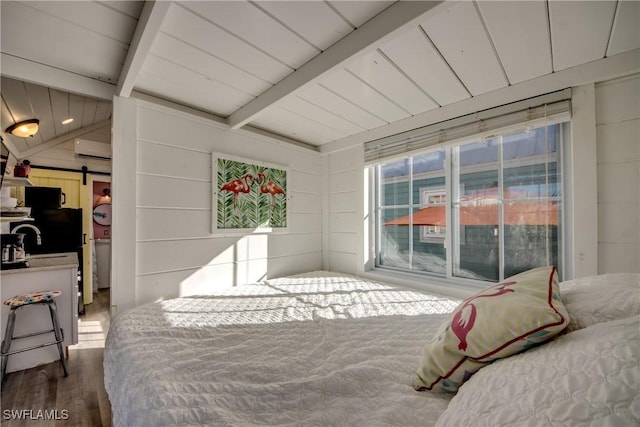 bedroom featuring wood walls, hardwood / wood-style flooring, vaulted ceiling with beams, a barn door, and a wall unit AC