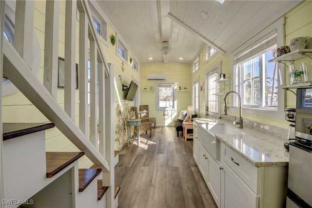 kitchen featuring wooden ceiling, vaulted ceiling, hardwood / wood-style flooring, light stone counters, and white cabinetry