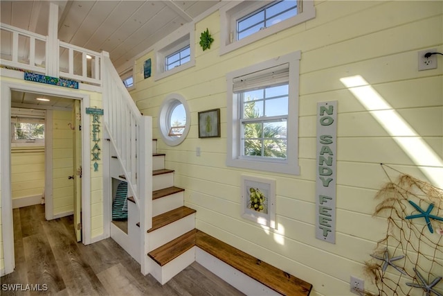 stairs featuring wood ceiling, wooden walls, and wood-type flooring