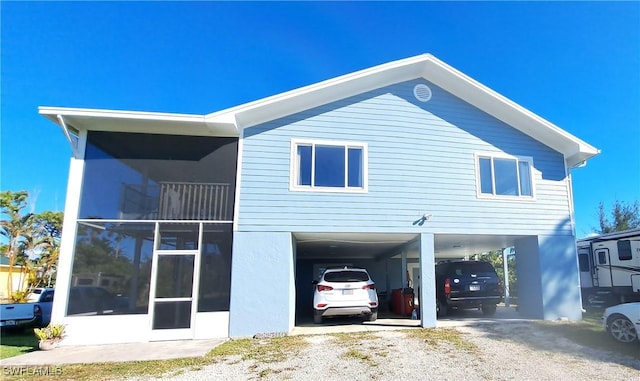 back of property featuring a sunroom and a carport