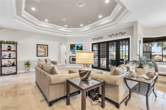 living room featuring a tray ceiling, french doors, and ornamental molding