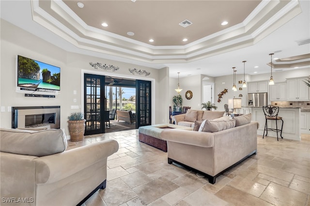 living room with french doors, a tray ceiling, and crown molding