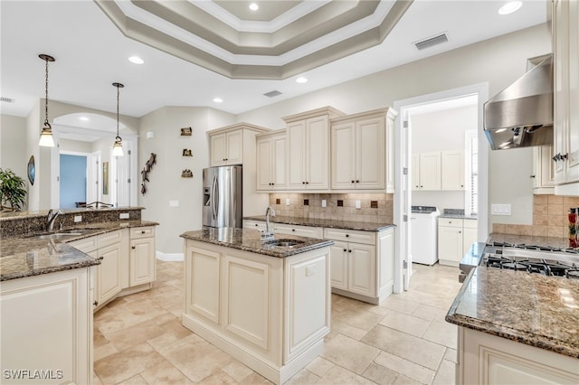 kitchen featuring sink, wall chimney range hood, tasteful backsplash, stainless steel fridge with ice dispenser, and a kitchen island with sink