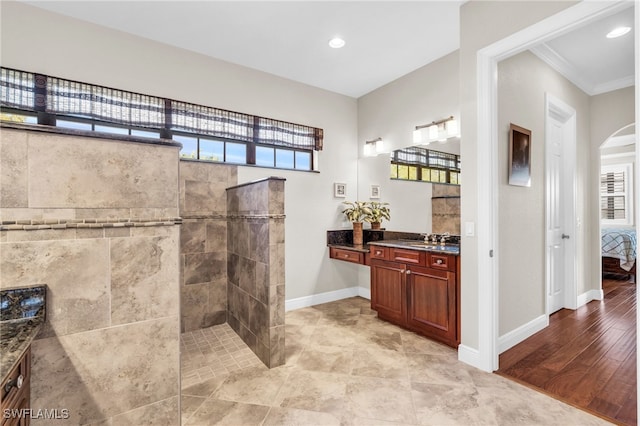 bathroom featuring hardwood / wood-style floors, vanity, a tile shower, and ornamental molding