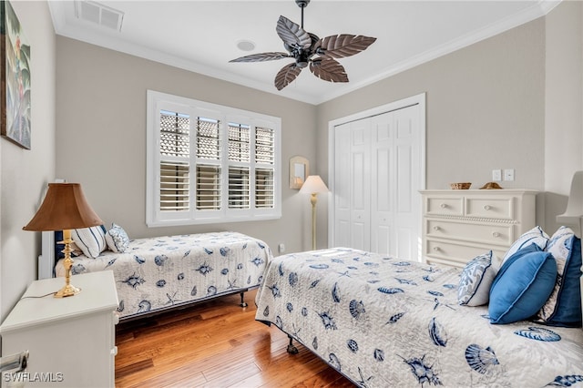 bedroom with crown molding, ceiling fan, a closet, and wood-type flooring