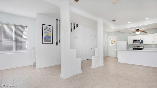 interior space featuring stainless steel appliances, white cabinetry, ceiling fan, and light tile patterned flooring