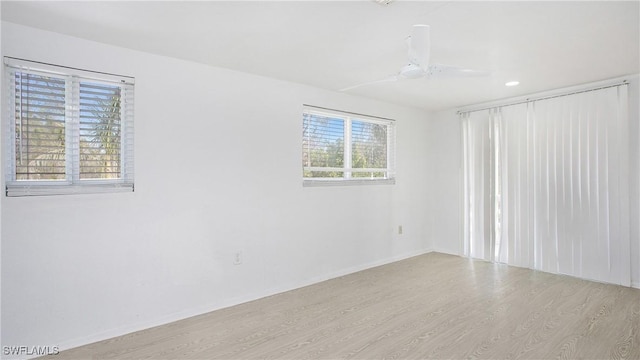 empty room featuring ceiling fan, a healthy amount of sunlight, and light hardwood / wood-style floors