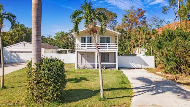 view of front of property featuring a front yard, a balcony, a garage, and an outdoor structure