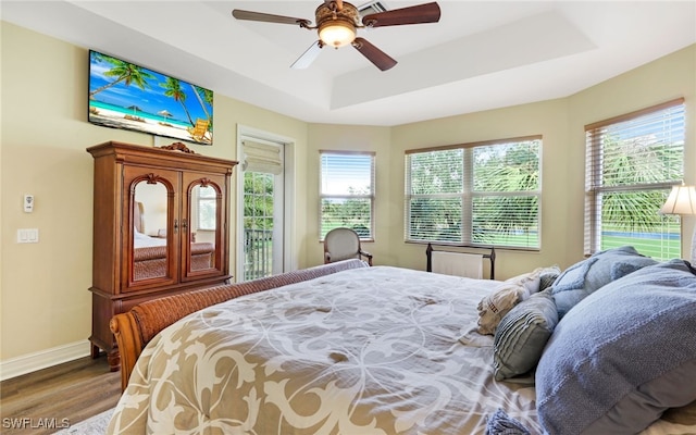 bedroom with hardwood / wood-style flooring, ceiling fan, and a tray ceiling