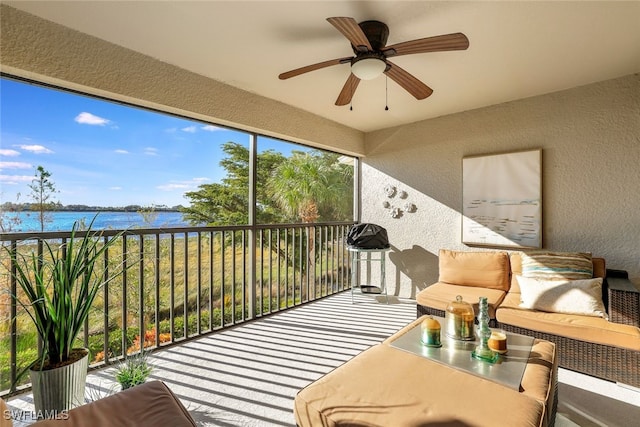 sunroom / solarium with ceiling fan and a water view