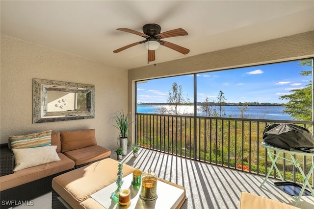 sunroom / solarium with ceiling fan and a water view