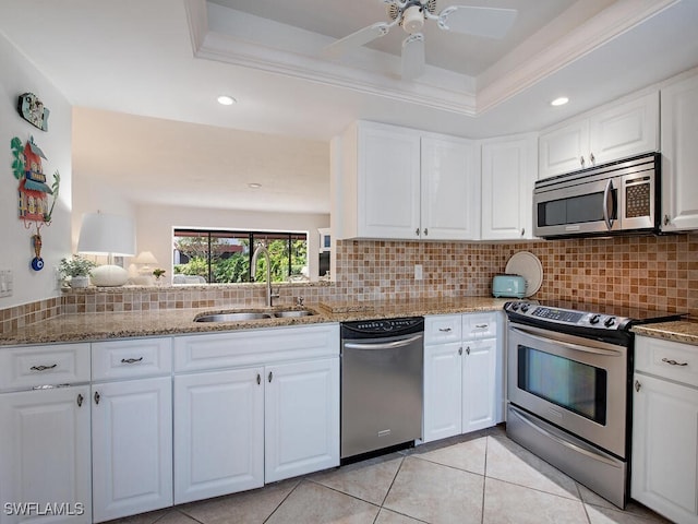 kitchen featuring decorative backsplash, appliances with stainless steel finishes, sink, light tile patterned floors, and white cabinetry