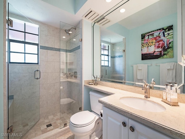 bathroom featuring vanity, toilet, and a shower with door