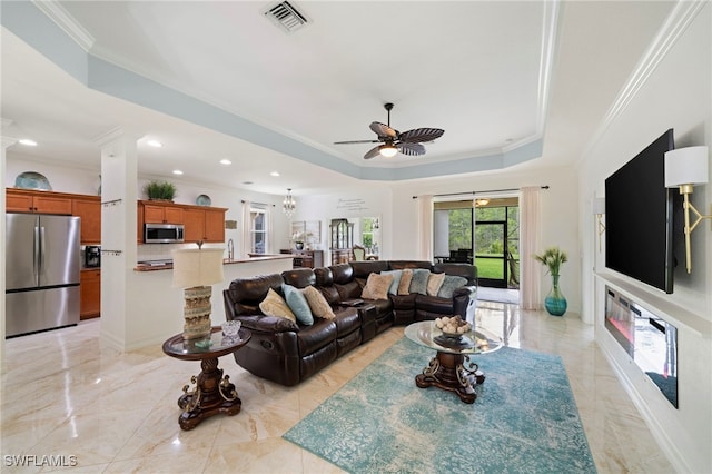 living room featuring visible vents, crown molding, a tray ceiling, ceiling fan with notable chandelier, and marble finish floor