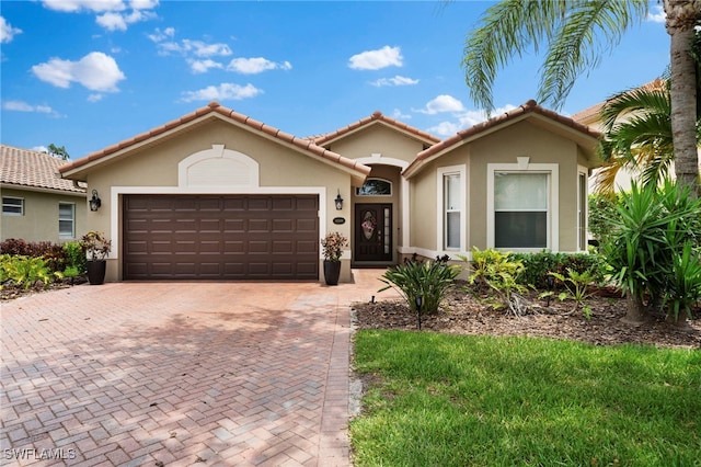 mediterranean / spanish house with stucco siding, decorative driveway, and a garage