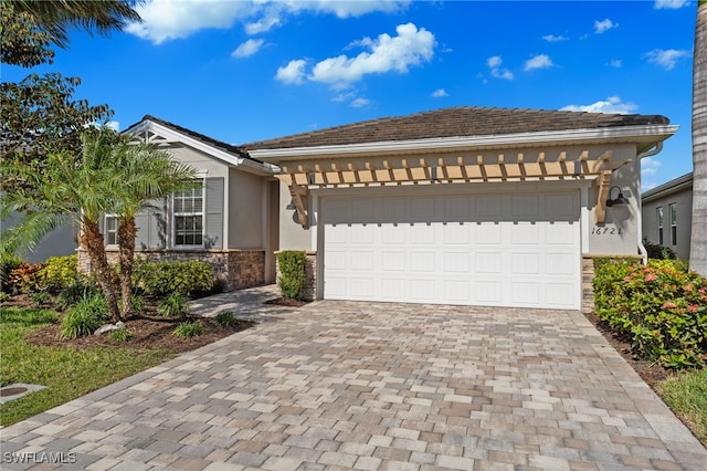 view of front of house featuring stone siding, stucco siding, decorative driveway, and a garage