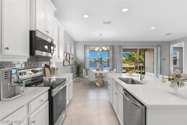 kitchen featuring appliances with stainless steel finishes, pendant lighting, white cabinetry, sink, and a notable chandelier