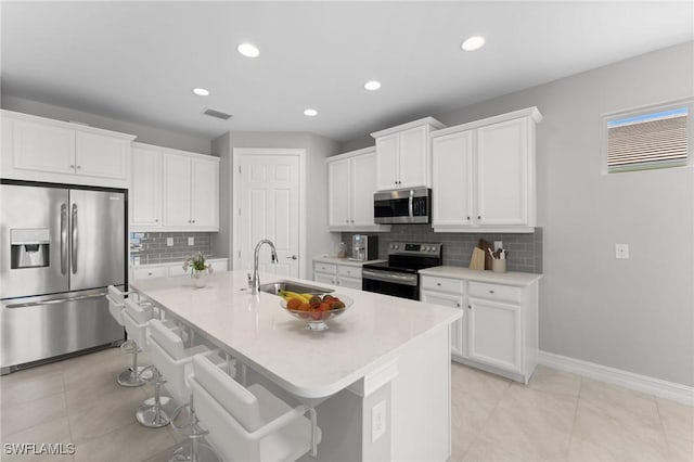 kitchen with stainless steel appliances, a breakfast bar, sink, and white cabinets