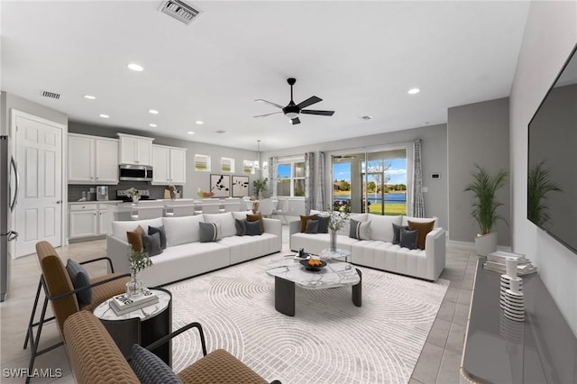 tiled living room with ceiling fan with notable chandelier