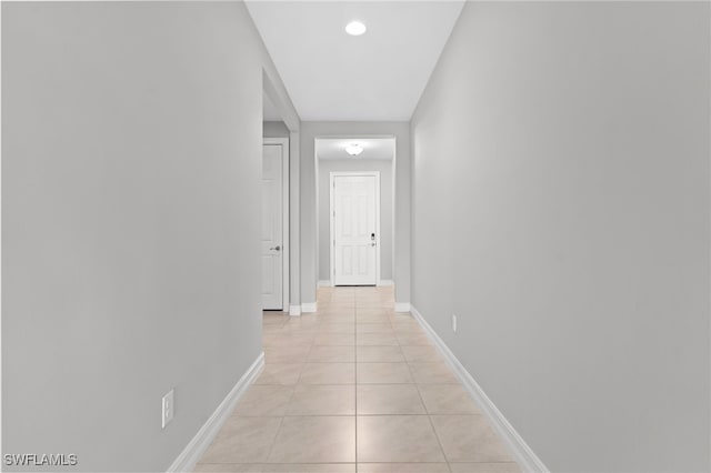 hall featuring baseboards and light tile patterned flooring