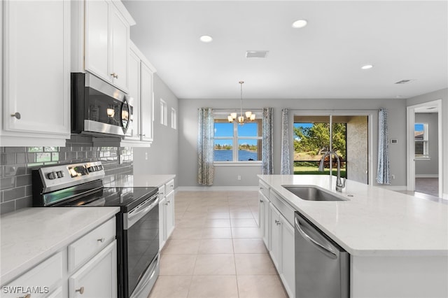 kitchen featuring sink, appliances with stainless steel finishes, white cabinetry, a kitchen island with sink, and decorative backsplash