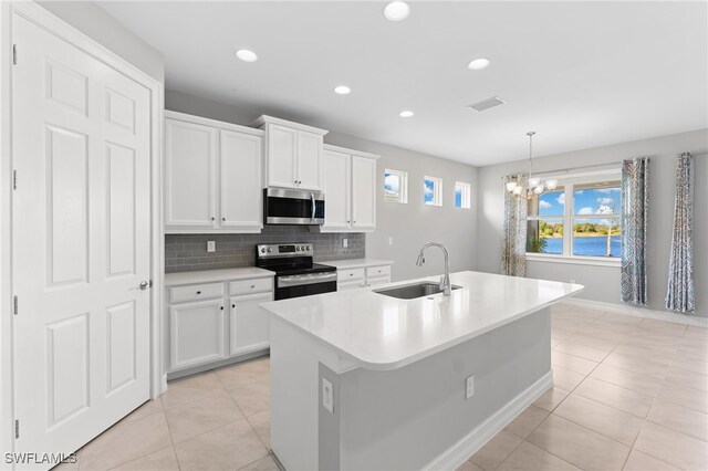 kitchen featuring sink, white cabinets, hanging light fixtures, a kitchen island with sink, and stainless steel appliances