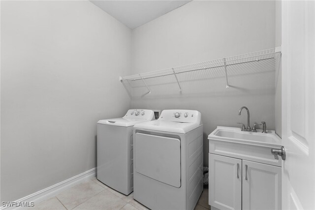 clothes washing area featuring cabinets, sink, washer and dryer, and light tile patterned floors