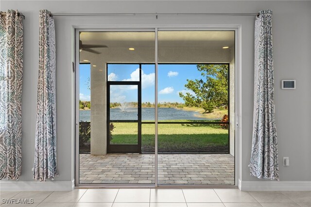 doorway featuring light tile patterned flooring, a water view, and a wealth of natural light