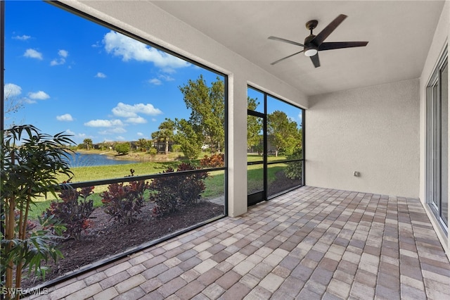 unfurnished sunroom featuring a ceiling fan and a water view