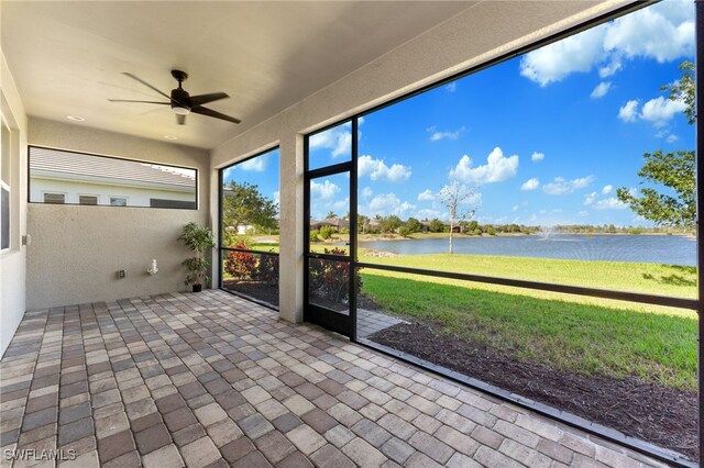 unfurnished sunroom featuring a water view and ceiling fan