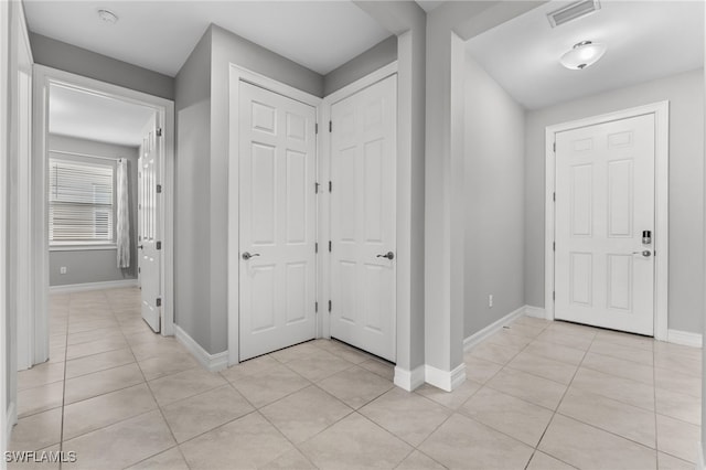 entryway featuring light tile patterned flooring, baseboards, and visible vents