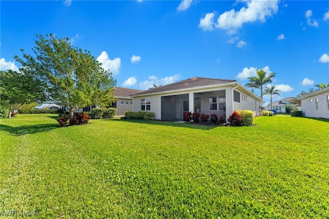 back of property with a sunroom and a lawn