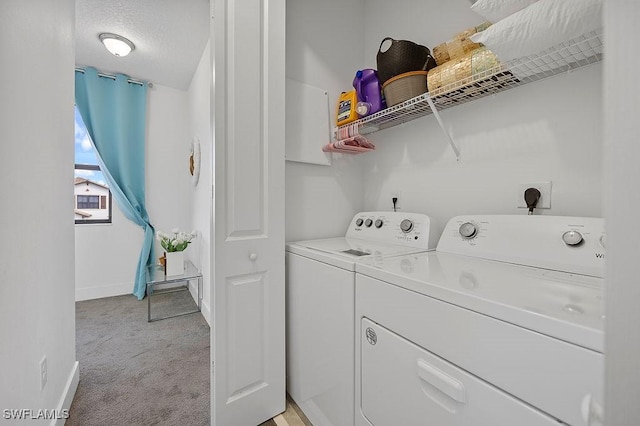 washroom featuring washing machine and clothes dryer, light carpet, and a textured ceiling