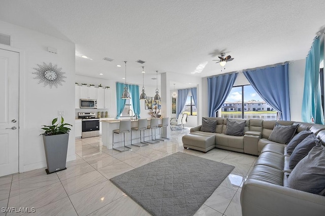 living room featuring ceiling fan and a textured ceiling