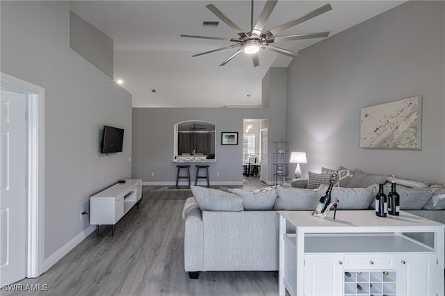 living room with light hardwood / wood-style floors, vaulted ceiling, and ceiling fan