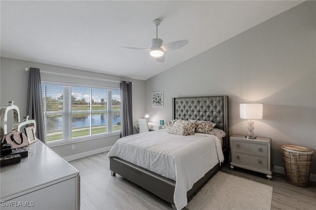 bedroom with ceiling fan, a water view, light wood-type flooring, and vaulted ceiling