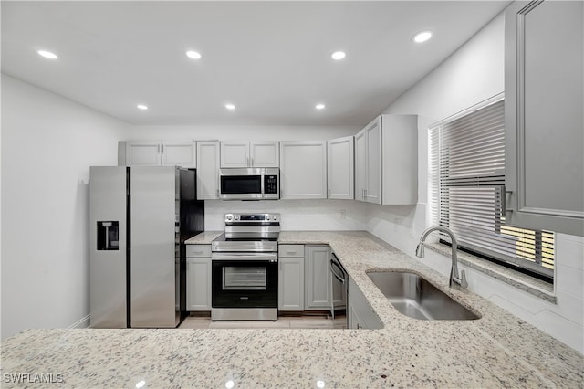 kitchen featuring backsplash, sink, gray cabinets, light stone countertops, and stainless steel appliances